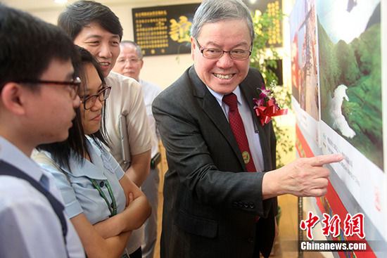 菲律宾福建晋江同乡总会理事长施亨利(右)为到场观展的华校学生临时客串讲解员。 中新社记者 张明 摄